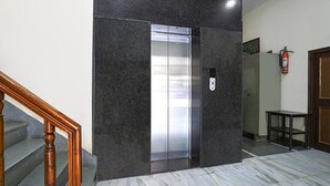 An elevator with a control panel, a fire extinguisher, and a wooden staircase. - Fabhotel Arjun (Nagpur)
