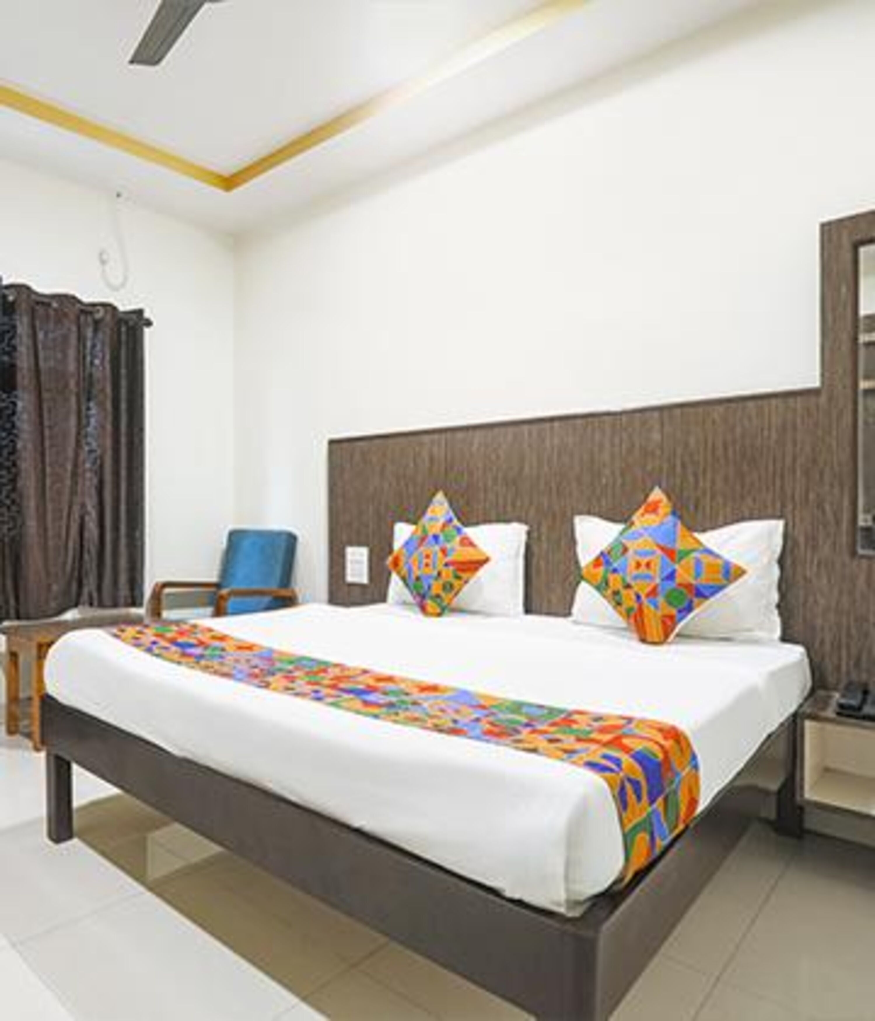 A hotel room with a bed, a chair, a nightstand, and a mirror.