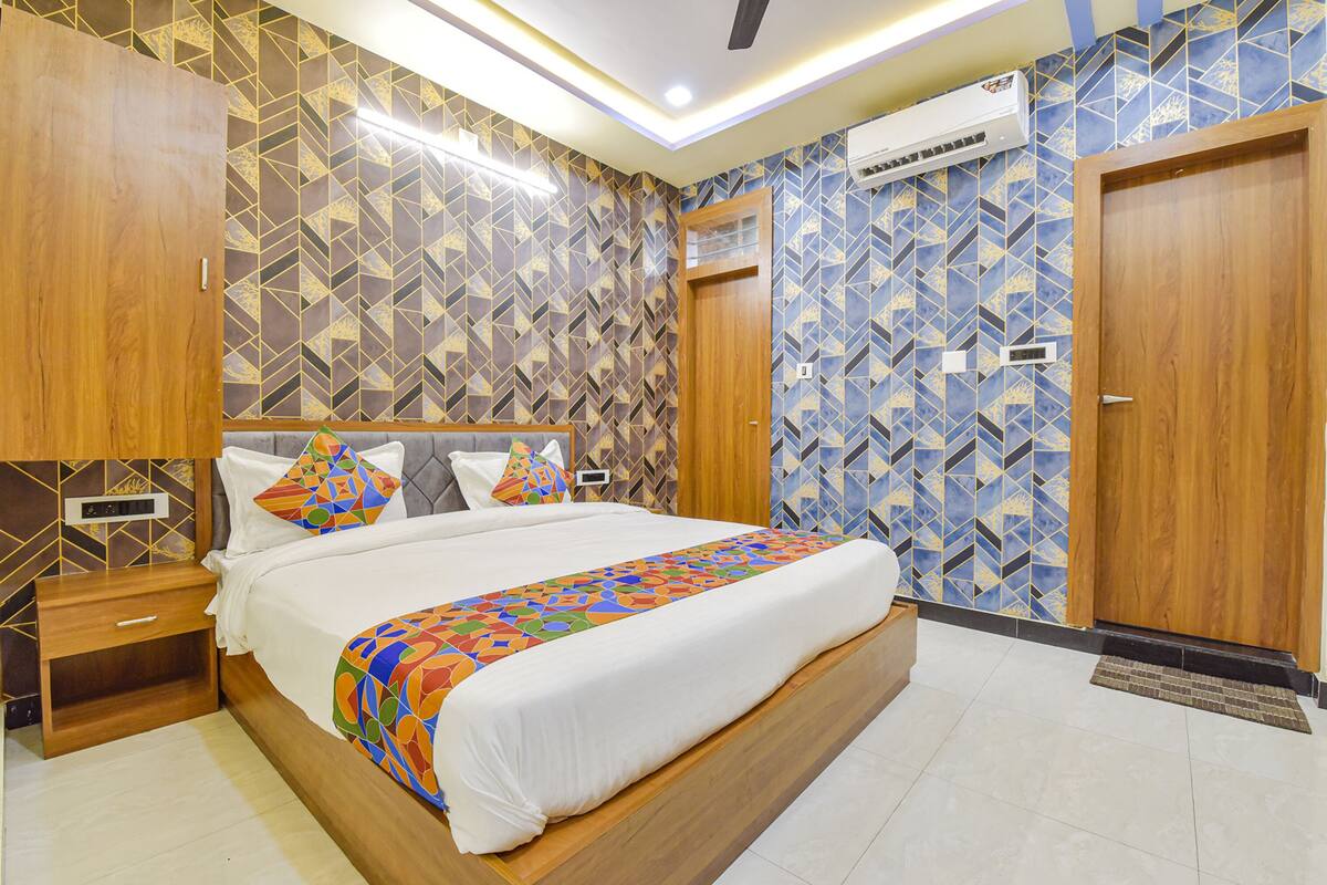 A modern bedroom with a large bed, wooden headboard, and patterned wallpaper.