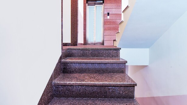 Un conjunto de escalones de granito que conducen a un ascensor en un edificio de diseño moderno.