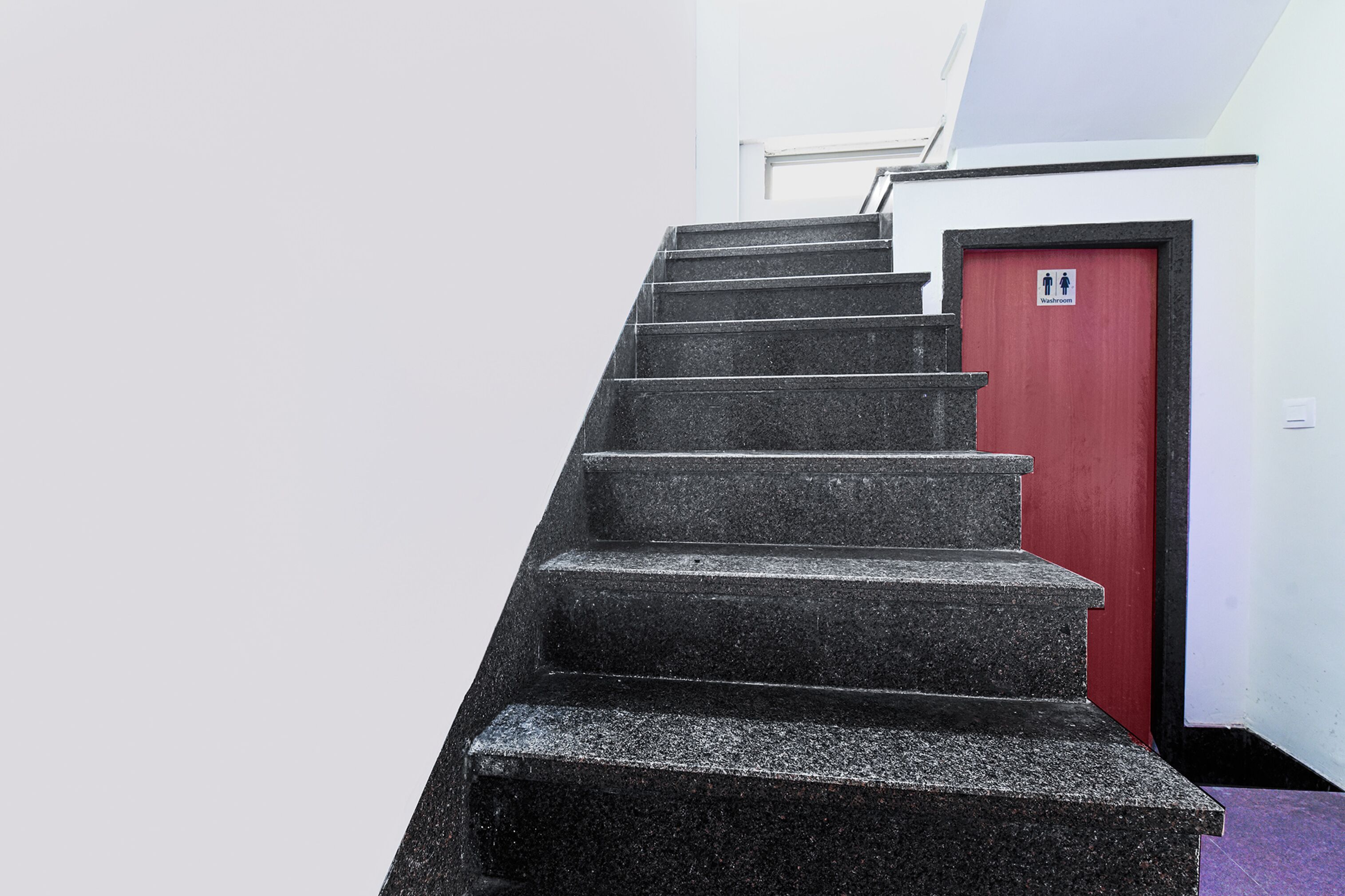 A staircase leading to a red door with a sign indicating a bathroom.