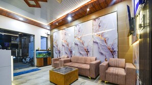 A modern interior with a sofa set, a glass coffee table, and a decorative wall with abstract patterns. - Fabhotel Grand Villa (New Delhi)