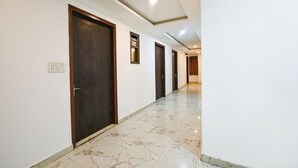 A hallway with marble flooring, wooden doors, and recessed ceiling lighting. - Fabhotel Grand Villa (New Delhi)