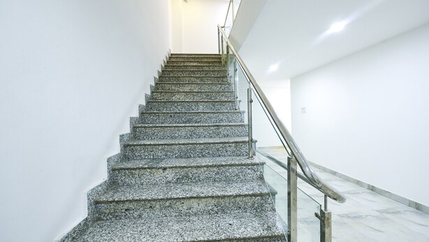 A staircase with a glass railing leading to a landing. - Fabhotel Grand Villa (New Delhi)