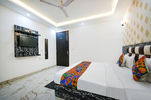 A bedroom with a bed, a TV mounted on the wall, a door, and a ceiling fan. - Fabhotel Grand Villa (New Delhi)