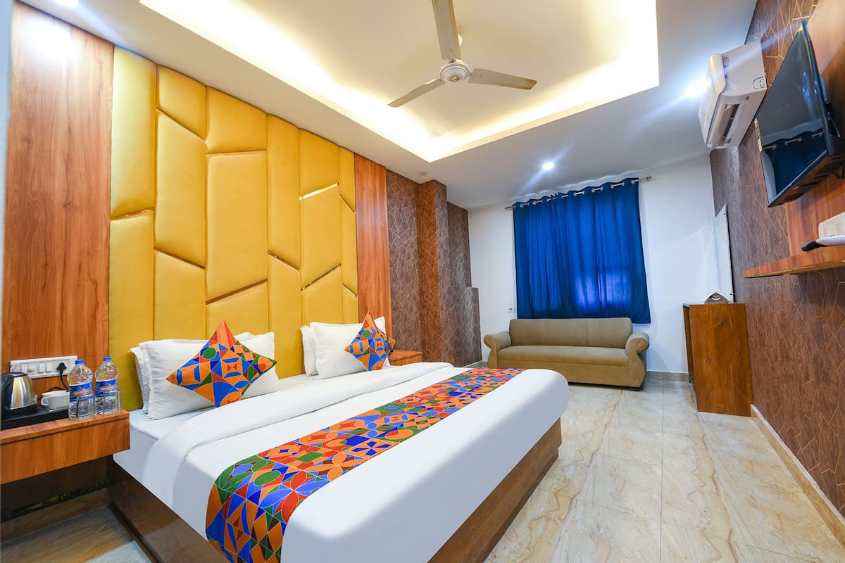 Una habitación de hotel con una cama grande, un sofá, un televisor y un ventilador de techo.