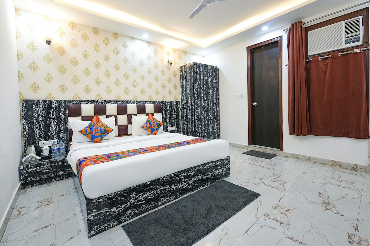 Un dormitorio ordenado con cama, mesita de noche y aire acondicionado instalado en la pared.