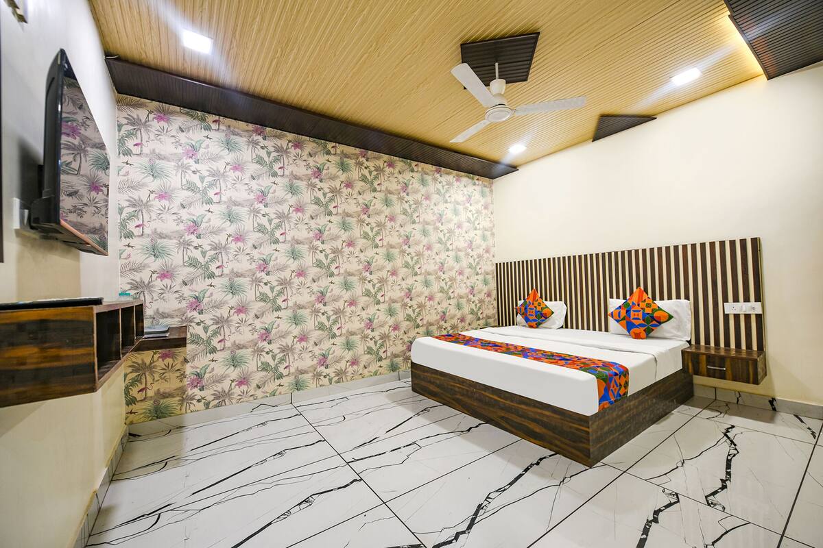 Ein Schlafzimmer mit einem Bett, einem Deckenventilator, einem Fernseher und einer Wand mit einem Blumenmuster.