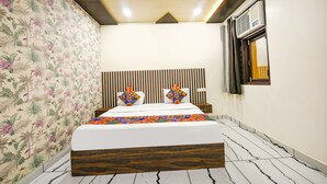 A bedroom with a bed, a ceiling fan, a window with curtains, and a wall with a floral pattern. - Fabhotel The Crystal Palace (New Delhi)