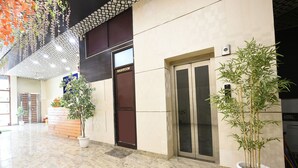 A clean, modern lobby with a reception desk, a washroom sign, and potted plants. - Fabhotel The Crystal Palace (New Delhi)