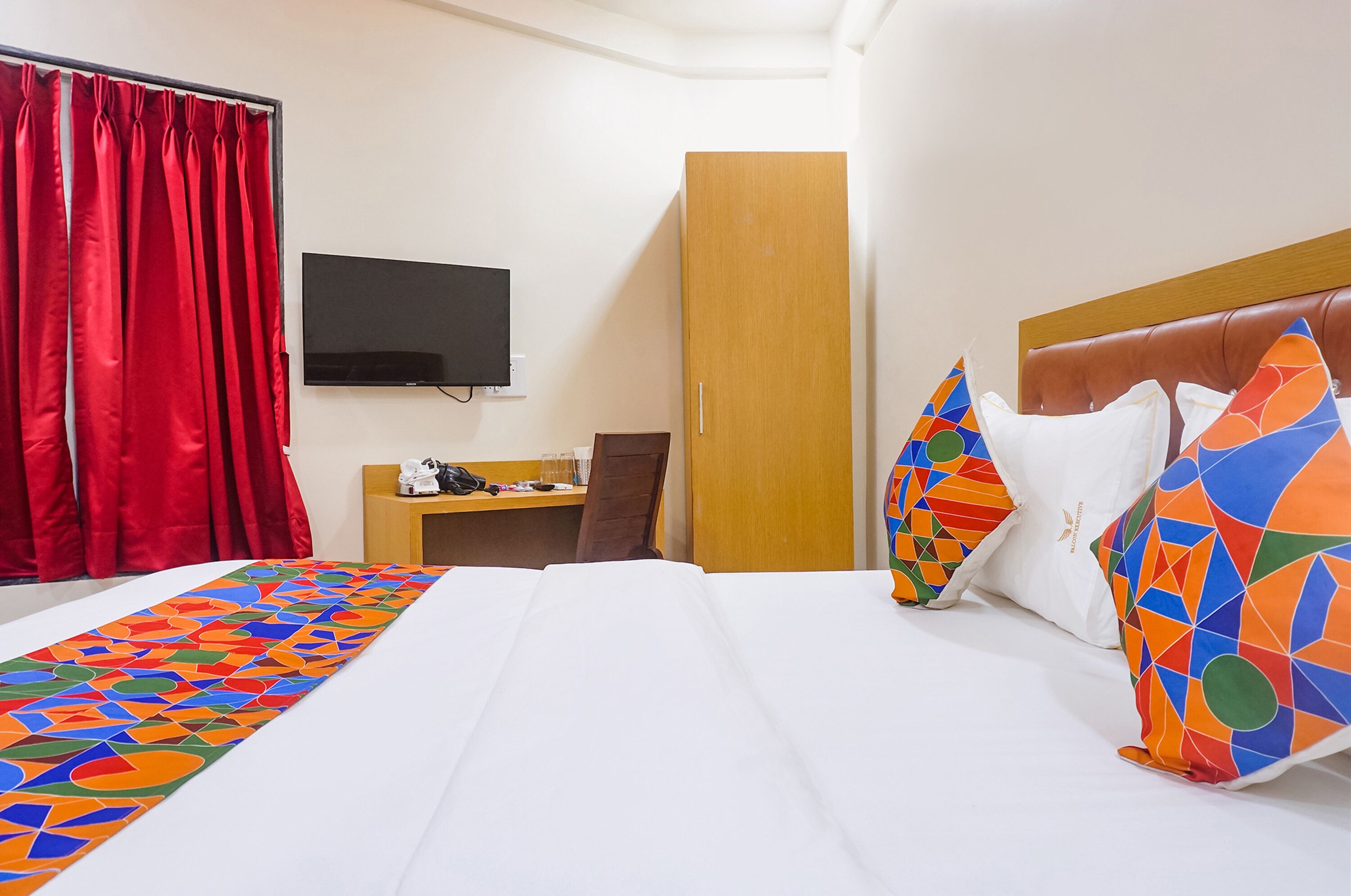 Una camera d'albergo con un letto, una scrivania, una televisione e un armadio.