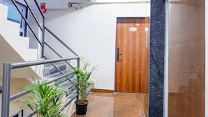A staircase with metal railings, a wooden door with a number plate, and potted plants. - Fabhotel Falcon Executive (Pune)