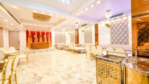 A spacious room with a marble floor, a sofa set, and a buffet area. - Fabhotel Royal'S Paradise (Faridabad)