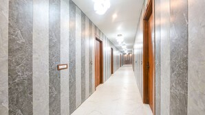 A long, narrow hallway with marble walls and doors, leading to multiple rooms. - Fabhotel Royal'S Paradise (Faridabad)