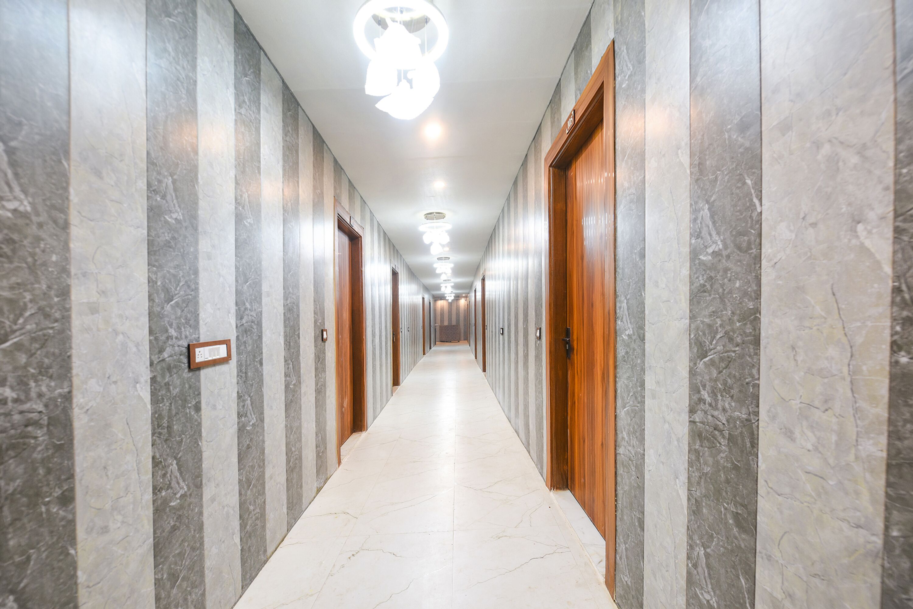 A long, narrow hallway with marble walls and doors, leading to multiple rooms.