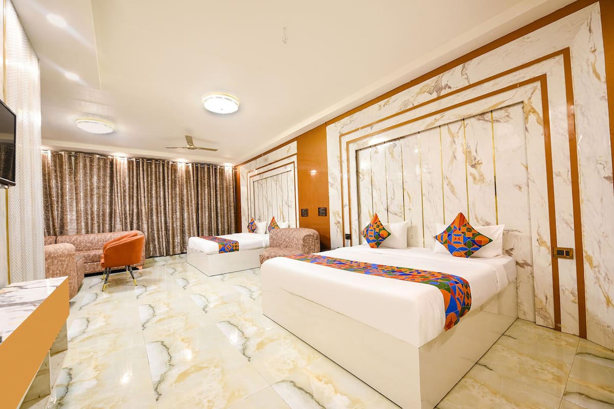 A hotel room with a large bed, a sofa, a desk, and a television.