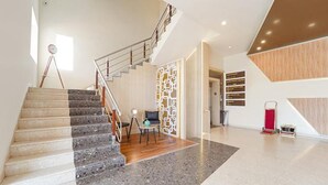 A modern interior with a staircase, a seating area, and a wall with directional signs. - Oriva Nestlay Rooms Ramnad (Ramanathapuram)