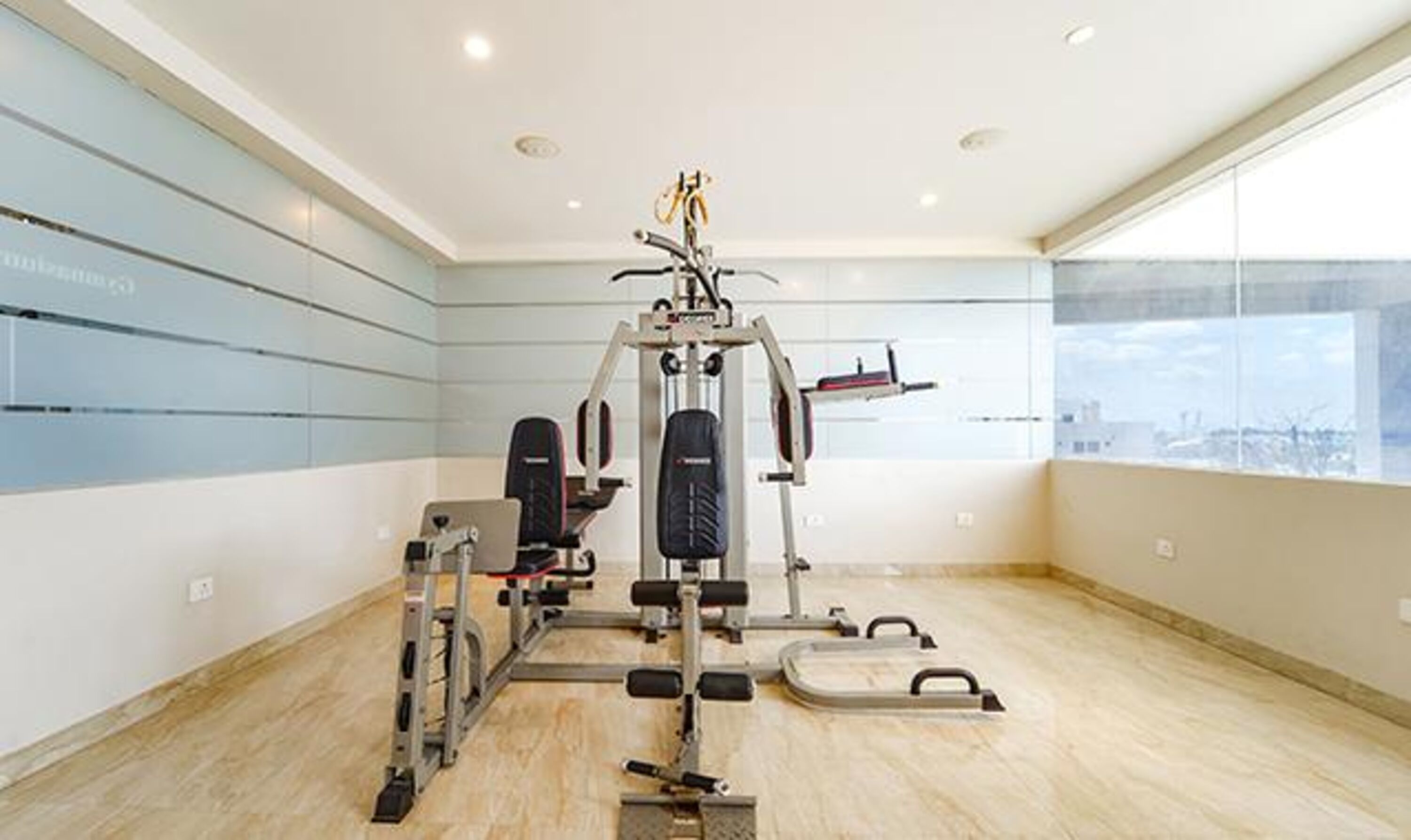 A gym with a variety of exercise equipment, large windows, and a view of the city.