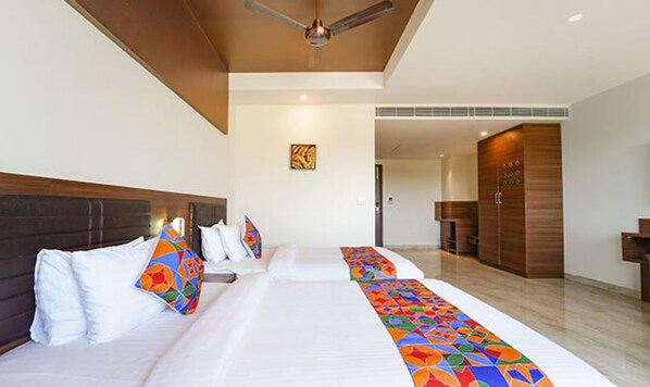 Una habitación de hotel con una cama grande, un ventilador de techo y un armario de madera.