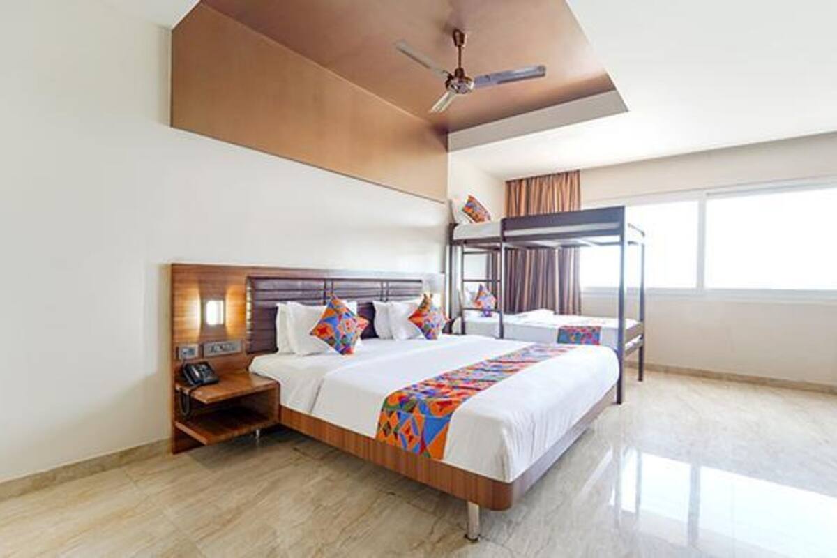 A hotel room with a bunk bed, a bedside table with a phone, and a ceiling fan.