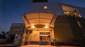 A modern building with a curved entrance canopy, steps leading up to the door, and a sign above the entrance. - Oriva Nestlay Rooms Ramnad (Ramanathapuram)