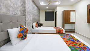 A hotel room with a large bed, a smaller bed, a wardrobe, a ceiling fan, and a tiled wall.