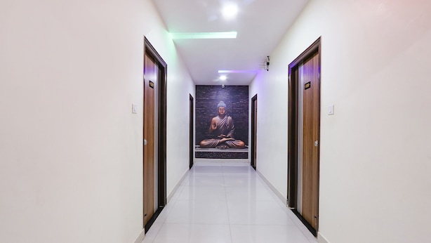 A hallway with a Buddha statue mural on the wall, wooden doors, and a tiled floor.
