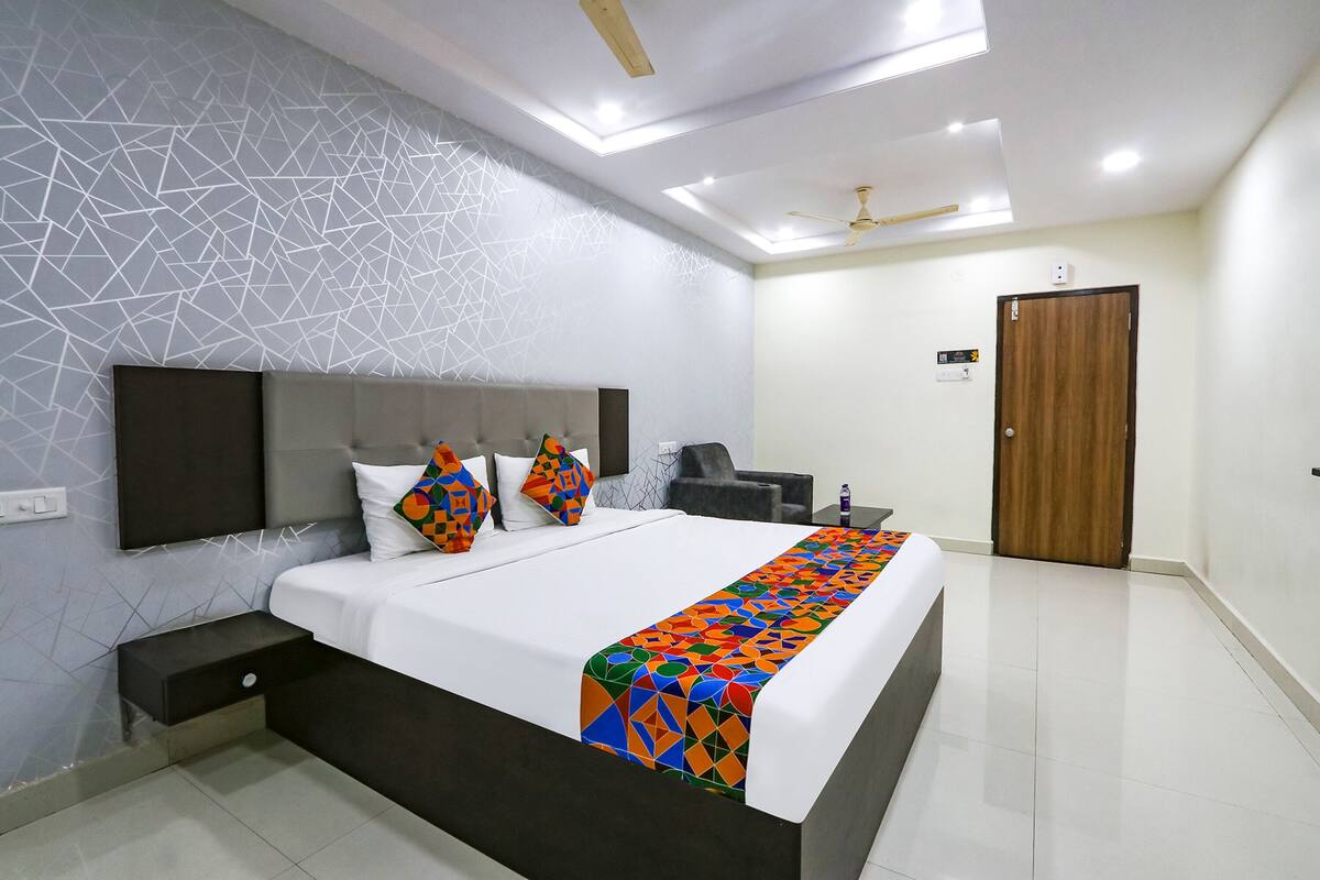 A modern bedroom with a bed, nightstands, a TV, a ceiling fan, and a wooden door.