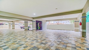 A spacious indoor area with a checkered floor, a reception desk, and a door leading to another room.