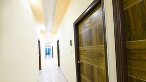 Hotellin käytävä, jossa on puinen ovi, jonka kyljessä lukee 206, laattalattia ja upotetuilla valaisimilla varustettu katto.