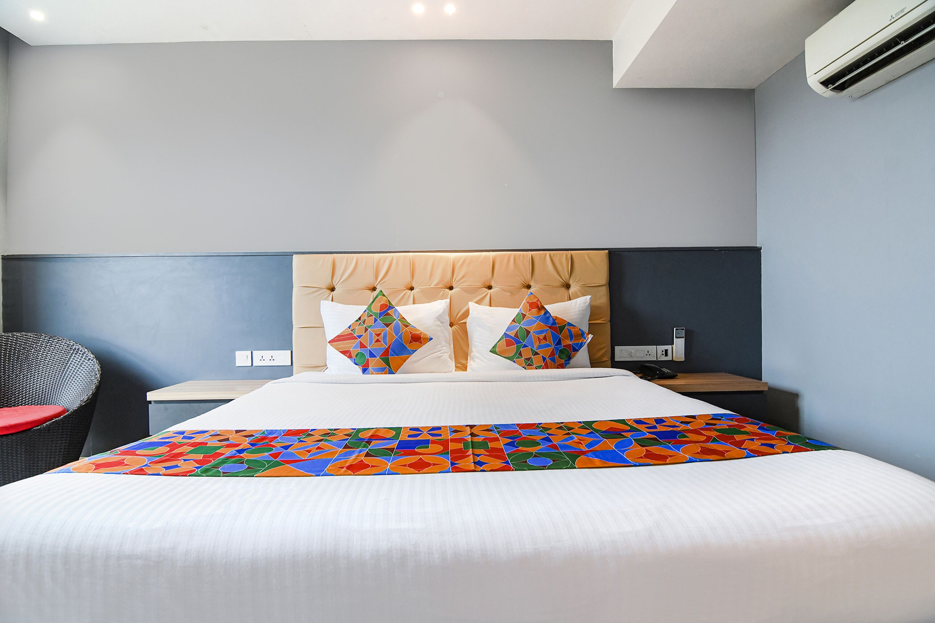 Ein Hotelzimmer mit einem Bett, einem Sessel, einem Nachttisch und einer Klimaanlage.