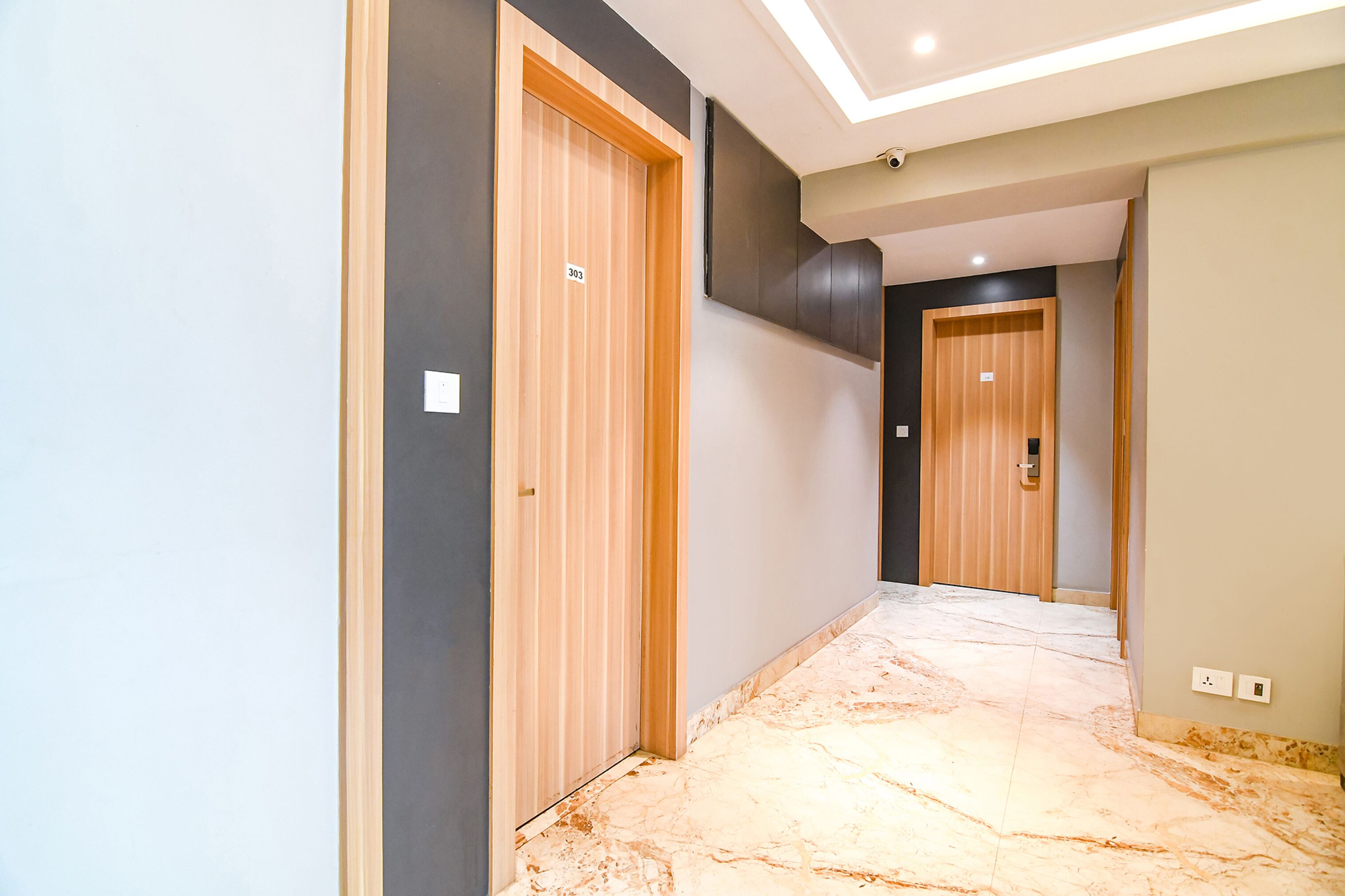 A hallway with wooden doors, a marble floor, and a ceiling light fixture.