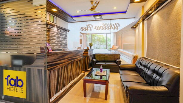 A hotel lobby with a reception desk, a sofa, and a coffee table. - Fabhotel Willow Tree (Bengaluru)