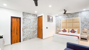 A bedroom with a bed, a sofa, a ceiling fan, and marble-patterned walls. - Fabhotel Prime Emporio Villa By Sbg (Ghaziabad)