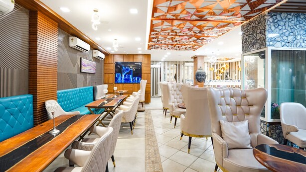 A modern restaurant interior with a long counter, cushioned seating, and a decorative ceiling. - Fabhotel Prime Emporio Villa By Sbg (Ghaziabad)
