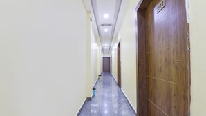 A long, narrow hallway with a wooden door on the right and a number sign above it. - Fabhotel Madhav (Mathura)