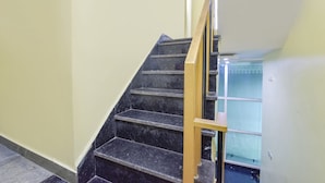 A staircase with black marble steps and a wooden handrail. - Fabhotel Madhav (Mathura)