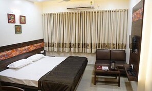 A hotel room with a bed, a sofa, a small table with a kettle, and a TV. - Fabhotel Rajdhani Ii (Nagpur)
