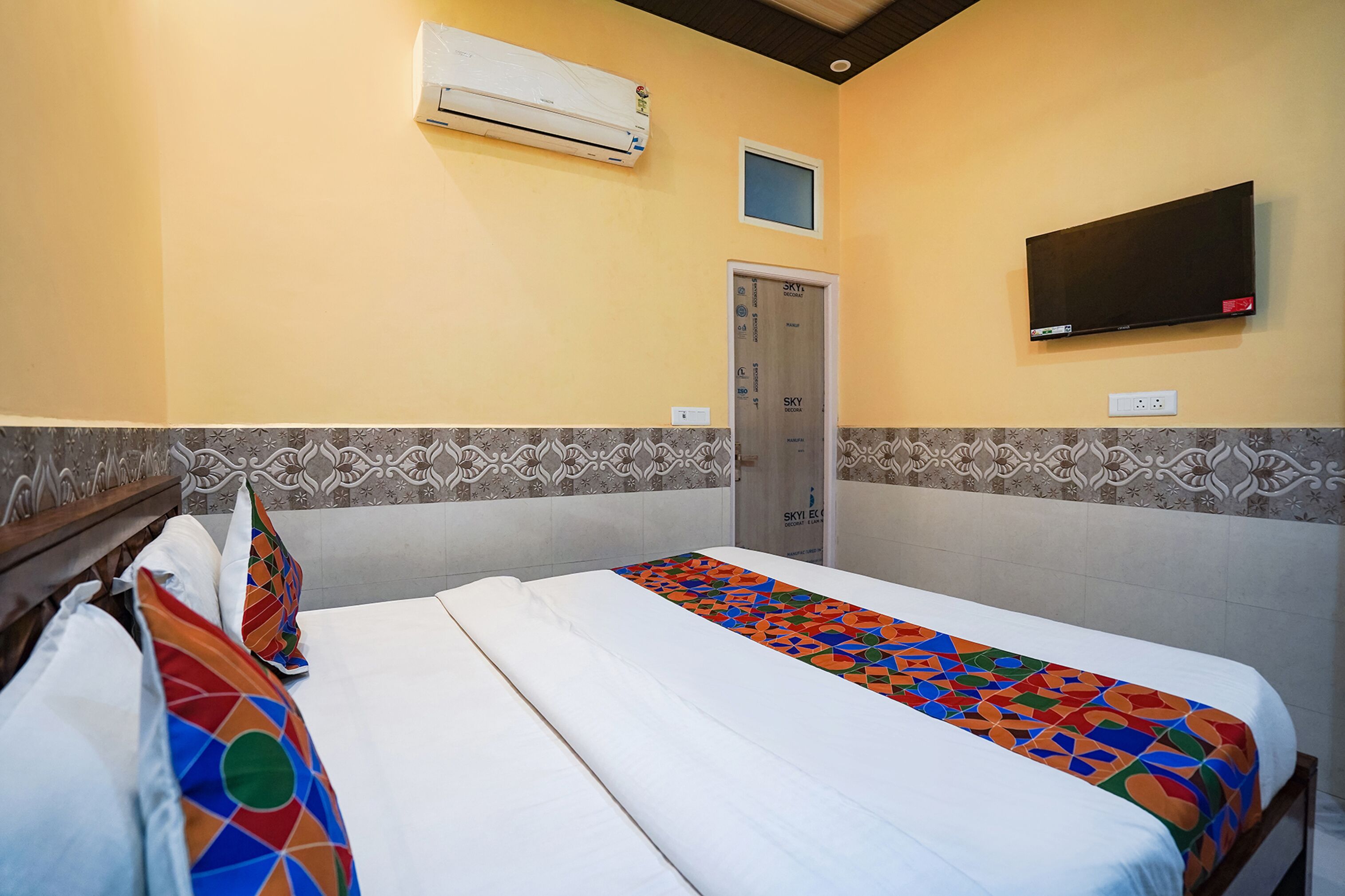 Habitación de hotel con dos camas, aire acondicionado, televisor y puerta con ventana.
