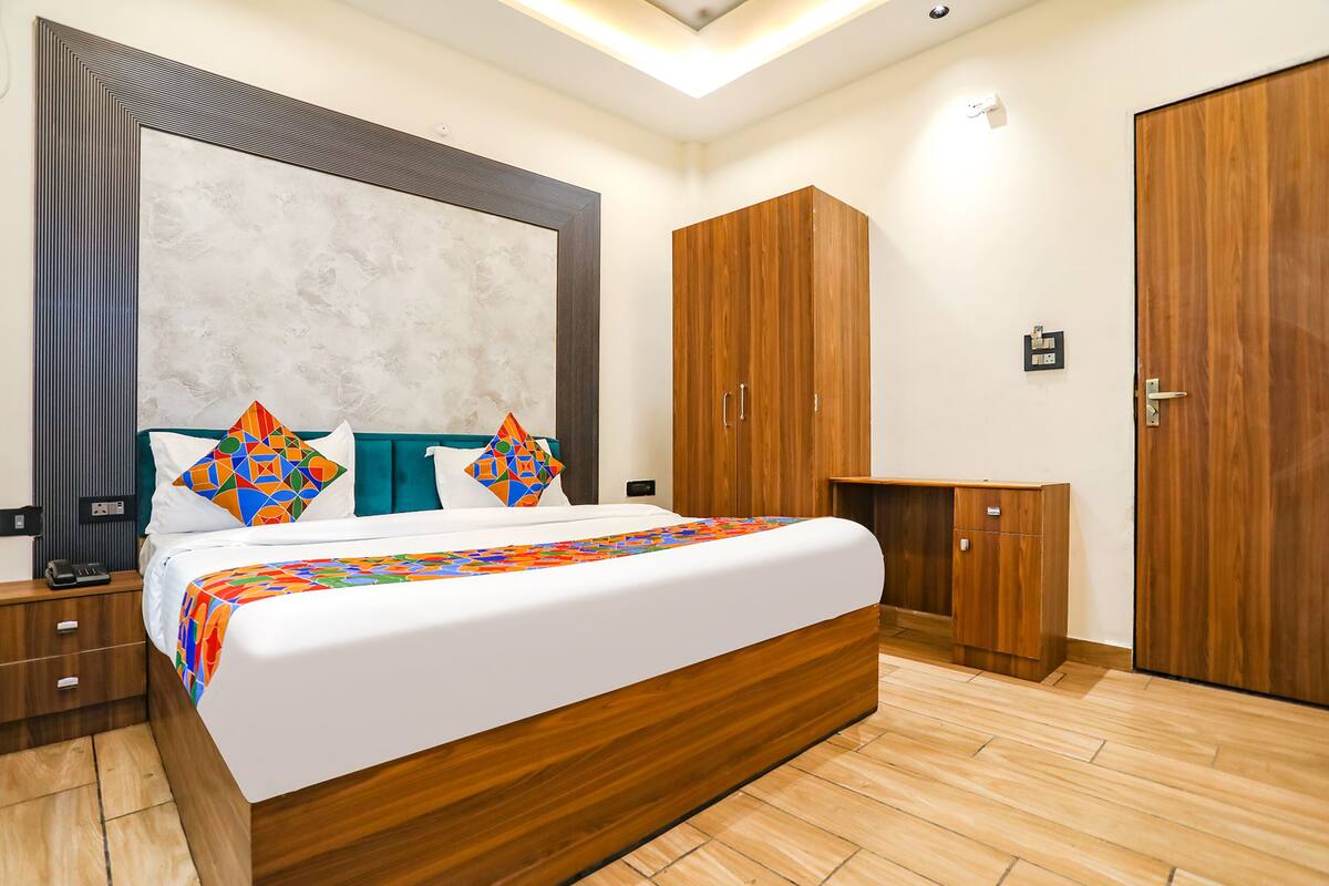 A modern bedroom with a large bed, wooden wardrobe, and a desk.