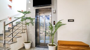 A hotel lobby with a marble staircase, a reception desk, and a large potted plant. - Fabhotel Vasudha (Mathura)