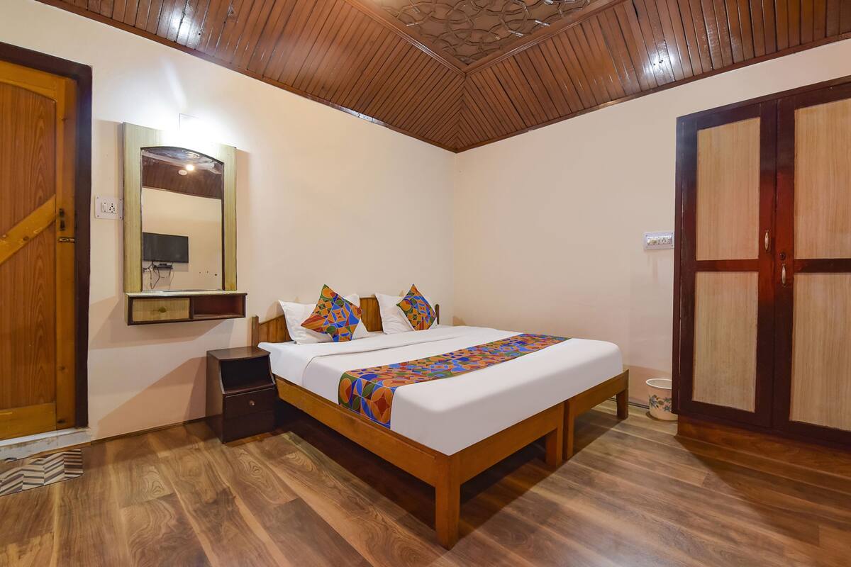 A bedroom with a wooden bed, a nightstand, a mirror, and a wardrobe.