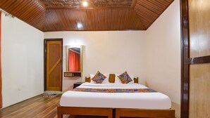 A bedroom with a wooden bed, a wooden door, and a red curtain. - Fabhotel Day'S Inn (Srinagar)