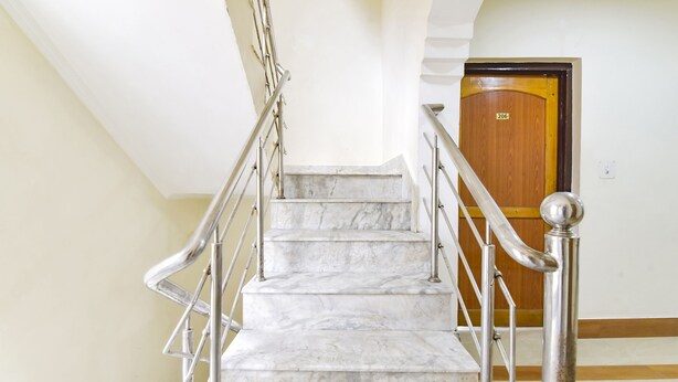 A marble staircase with metal railings and a wooden door with the number 206. - Fabhotel Day'S Inn (Srinagar)