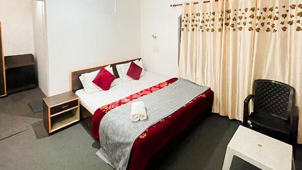 A hotel room with a bed, a nightstand, a chair, and a curtain. - Fabhotel Ta Hayaat (Srinagar)
