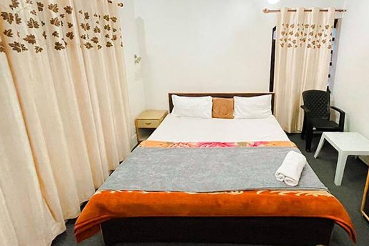 A hotel room with a bed, a desk, a chair, and a wardrobe.