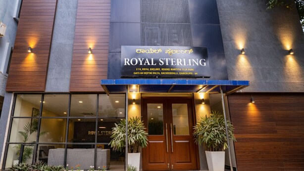The exterior of the Royal Sterling hotel with a signboard, entrance, and potted plants. - FabHotel Royal Sterling (Bengaluru)