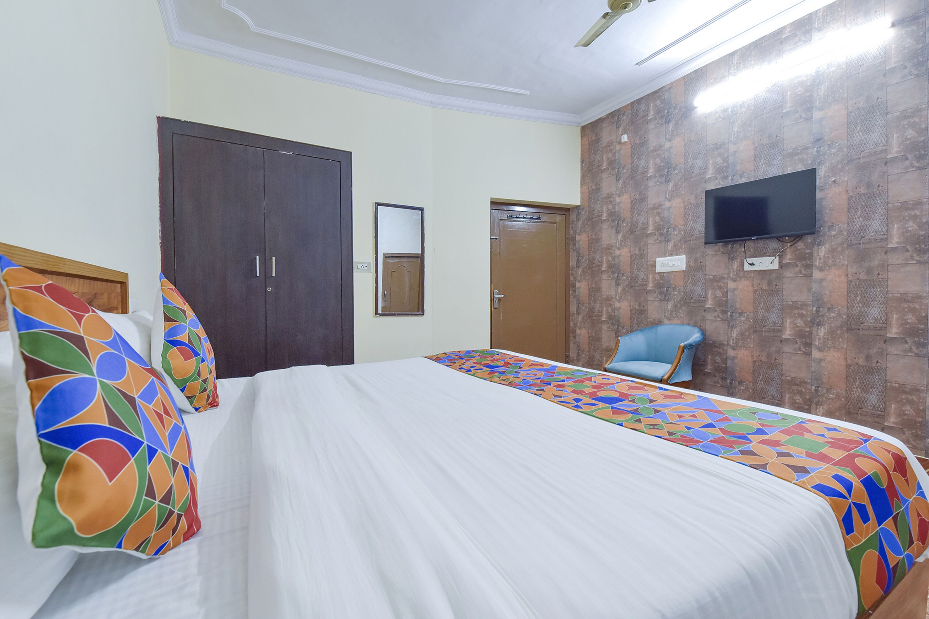 Una camera d'albergo con un letto, un armadio, una televisione e una sedia.