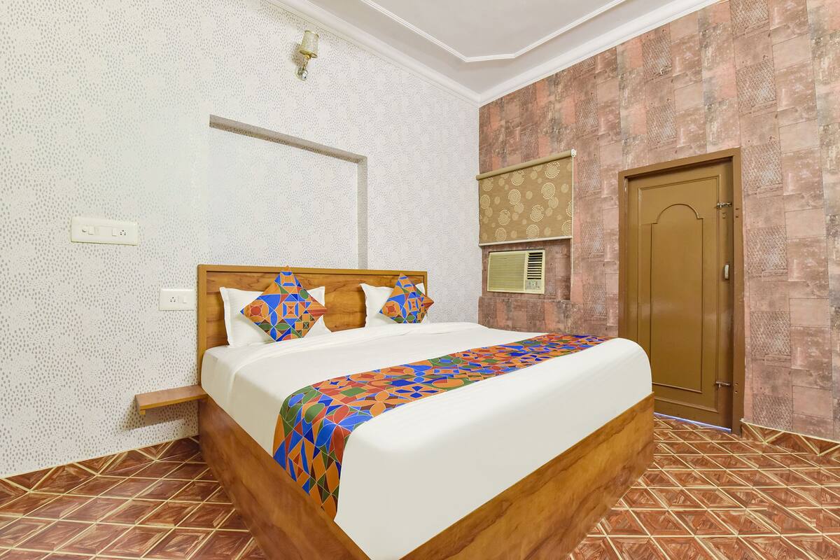 A neatly made bed with a patterned bedspread, a wooden headboard, and a small bedside table.
