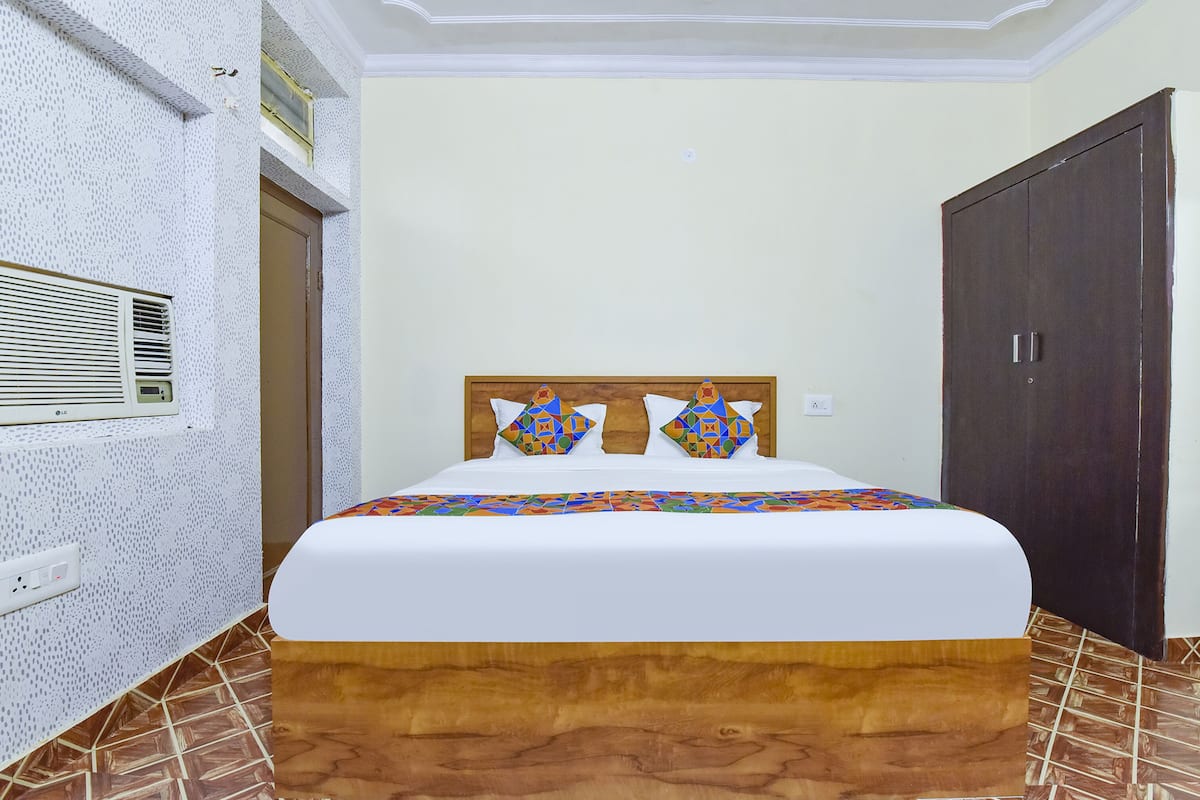 A neatly made bed with a wooden headboard, two decorative pillows, and a white bedspread.